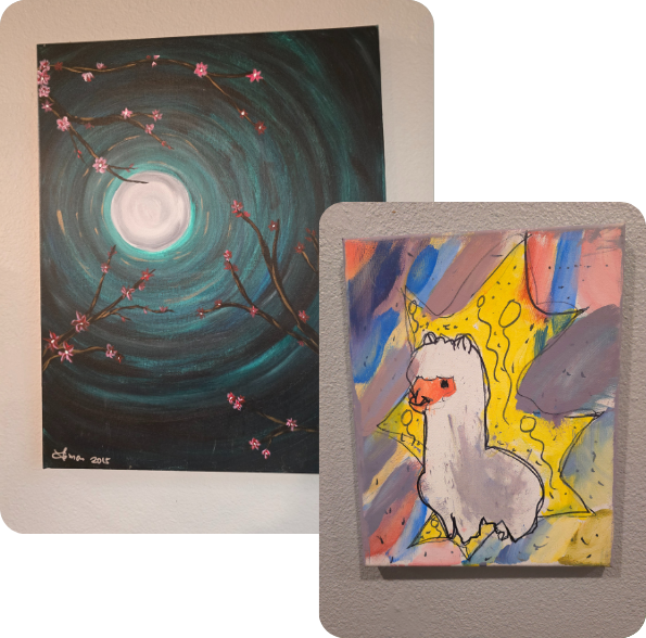 Two art pieces, one behind the other. The back piece is a dark black and team circular swirl around a moon, with dark brown branches and cherry blossoms around it. The front canvas is a white and grey llama with a brightly coloured background